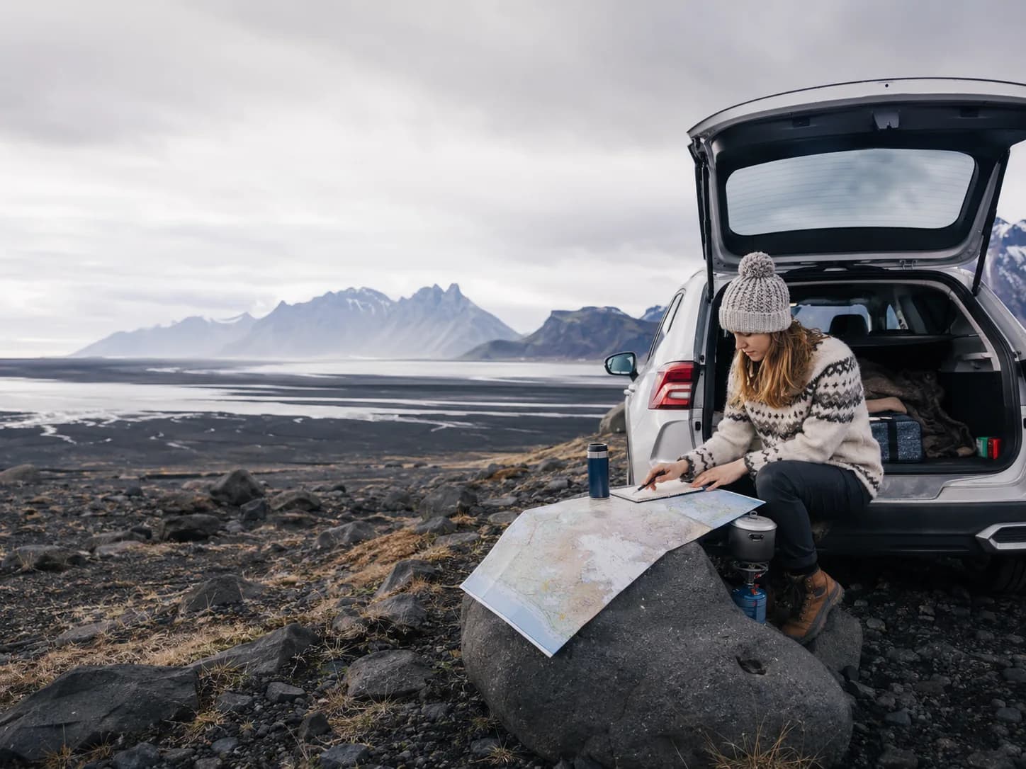 Traveller planning an Iceland road trip beside volcanic terrain and distant mountains